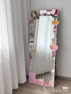 a mirror that is sitting on the floor next to a window with curtains behind it