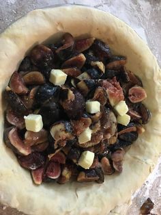 an uncooked dough with figs and cheese in it sitting on a table