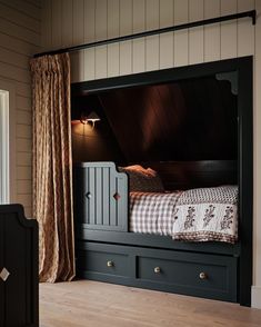 a bunk bed with drawers underneath it in a room that has wood floors and walls