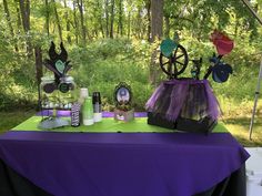 the table is set up with purple and green decorations, including an umbrella, witch hat, spider web, eyeglasses, candles, and other items