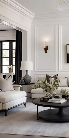 a living room filled with white furniture and lots of black and white decor on the walls