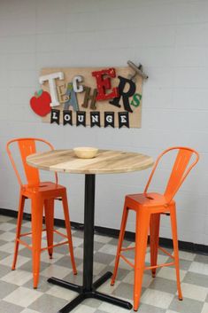 two orange chairs sitting at a table in front of a sign that says eat here