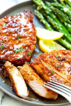 grilled pork chops, asparagus and lemon wedges on a plate