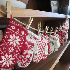 knitted mittens hanging from clothes pins on a shelf