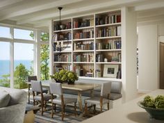 a living room filled with furniture next to a large window covered in bookshelves