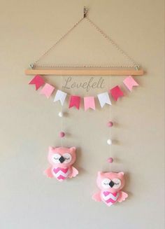 a pink and white teddy bear mobile hanging from a wall