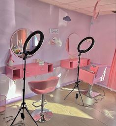 two pink chairs in front of mirrors with lights on them