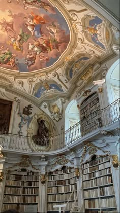 the interior of a library with many bookshelves and paintings on the ceiling above them