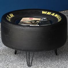 a black tire sitting on top of a floor next to a blue wall and magazine rack