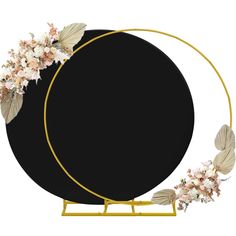 a black and gold circle with white flowers on the top is surrounded by leaves and petals