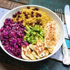 a white bowl filled with meat, rice and veggies next to a fork