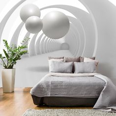 a large bed sitting in a bedroom next to a white vase filled with green plants