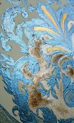 an intricate blue and gold design on a glass vase with glittery flecks