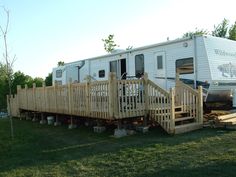 a mobile home with stairs leading up to the front door and back deck in an open field