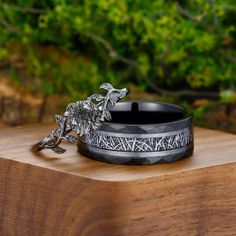 two black rings sitting on top of a wooden table next to each other and trees in the background