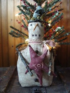 a snowman with a hat and star on it's head sitting next to a christmas tree