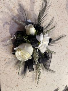 a bouquet of white flowers and feathers on a marble surface with some scissors next to it