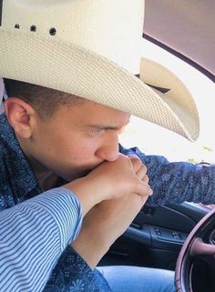 a man wearing a cowboy hat sitting in the driver's seat of a car