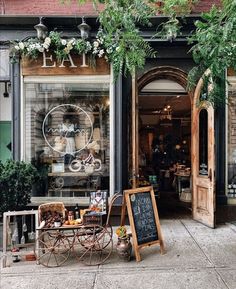 an outside view of a store with plants and furniture