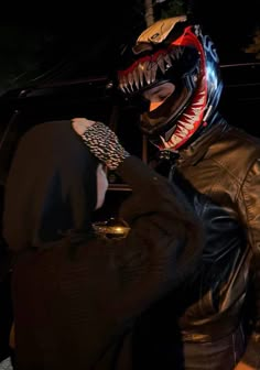 a man in a leather jacket with a large snake head on his arm, holding onto a cell phone