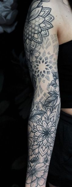 a woman's arm with black and white flowers on her sleeve, in front of a dark background