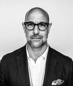 a black and white photo of a man with glasses wearing a suit jacket, shirt and tie