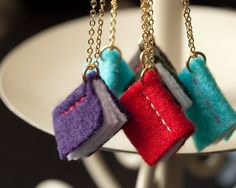 three pieces of felt hanging from chains on a white plate with a black table in the background