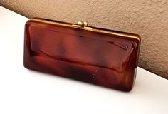 Vintage orange/brown  tortoiseshell vanity purse. Rectangular with gold tone metal frame and closure. Inside there is a large pocket with mirror, golden satin lining and openings for powders case, lipstick. This bag is in a good vintage condition with normal wear due to vintage age -  there are a few subtle scratches, the corner has light cracks, however it does not go inside. hardware and mirror also with signs of wear The interior part is clean. Please, refer pictures.  Dimensions: width - 22 Vintage Cosmetic Bag, Elegant Evening Bags In Tortoiseshell, Brown Compact Formal Bag, Compact Brown Formal Bag, Vintage Makeup Bag, Makeup Purse, Lipstick Bag, Lipstick Case, Vintage Cosmetics