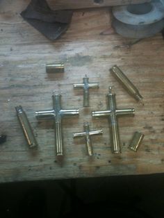 several metal crosses on a wooden table with some tools in the background and one is missing