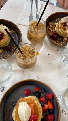 pancakes, fruit and ice cream are served on plates at a table with glasses of water