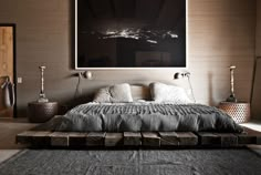 a bed sitting on top of a wooden platform next to a wall mounted art piece