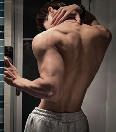 a shirtless man taking a selfie in front of a mirror with his cell phone