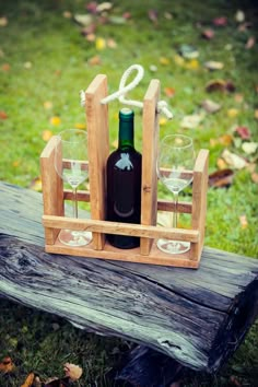 two wine glasses and a bottle in a wooden crate