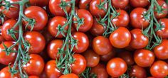 a bunch of tomatoes with green stems on them are piled high in the air and ready to be eaten