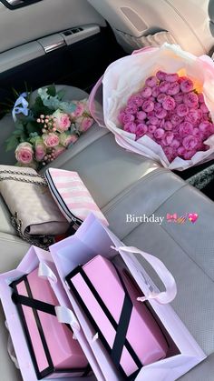 pink roses are sitting in the back seat of a car, and one is wrapped in white paper