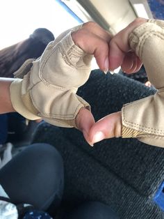 two hands with gloves on sitting in a bus seat, one holding the other's thumb