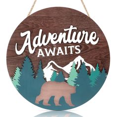 a wooden sign that says adventure awaits with a bear in the woods