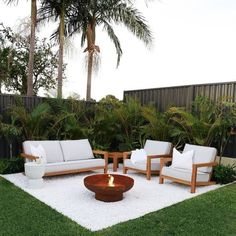 a fire pit in the middle of a yard with chairs and couches around it