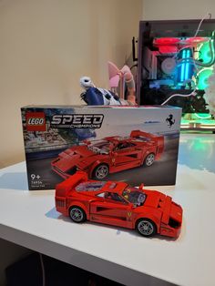 a red lego car sitting on top of a table next to a box with the word speed written on it