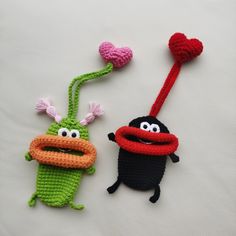 two crocheted toys are sitting next to each other on a white surface,