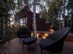 two black chairs sitting on top of a wooden deck next to some trees and lights