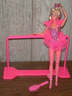 a barbie doll standing next to a pink brush