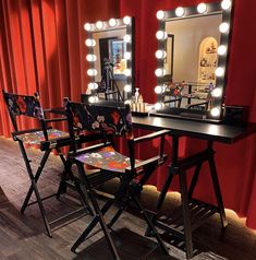 two chairs are sitting in front of a vanity with lights on it and a mirror behind them