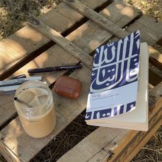 an open book sitting on top of a wooden table next to a jar of liquid