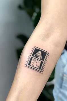 a person's arm with a small dog in the window tattoo on their left forearm