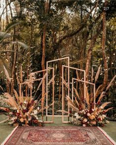 an outdoor ceremony setup with tall grass and flowers on the ground, surrounded by trees