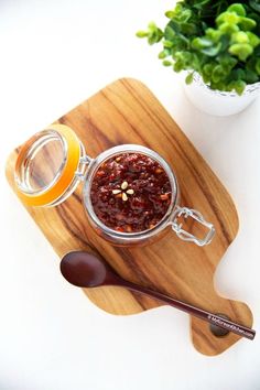 a jar of jam next to a spoon on a cutting board