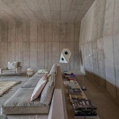 a living room filled with lots of furniture next to a wall covered in cement walls