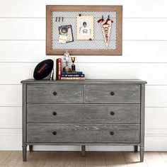 a gray dresser with some books on top of it and a framed picture above it