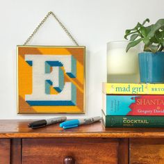 a wooden dresser topped with books and a vase filled with flowers next to a candle